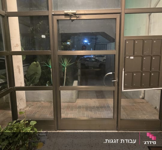 דלת כניסה ומחיצת זכוכית במסגרת אלומיניום בלובי של בניין